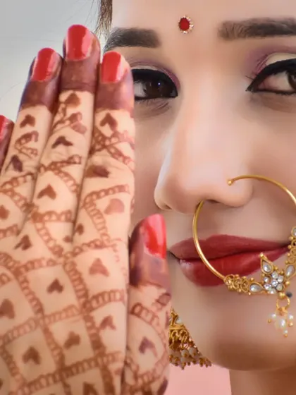 A close-up, artistic shot focusing on the bride's eye, nose ring, and the intricate mehndi pattern on her hand.