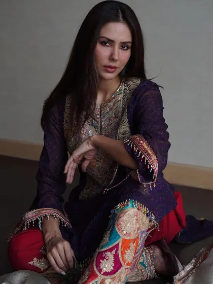 A contemplative pose that draws attention to the stunning, colorful embroidery on the pants of this Rimple and Harpreet ensemble.
