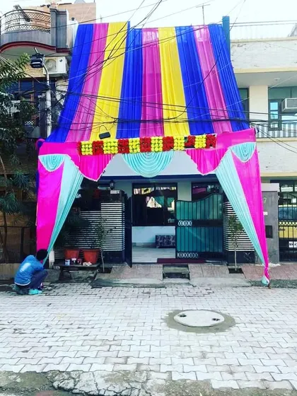 A house entrance covered with a canopy of blue, yellow, and pink drapes, creating a colorful welcome for guests.
