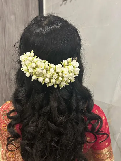 A half-up hairstyle with soft curls, decorated with a traditional gajra of jasmine flowers. The fragrance and beauty of real flowers is unmatched.