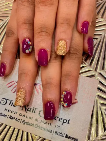 A rich and royal look with square-shaped nails. This set features a deep magenta polish, gold glitter accent nails, and accent nails with clusters of iridescent crystals.