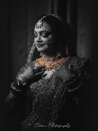 A stunning black and white bridal portrait with selective coloring on her gold jewelry, creating a striking contrast.
