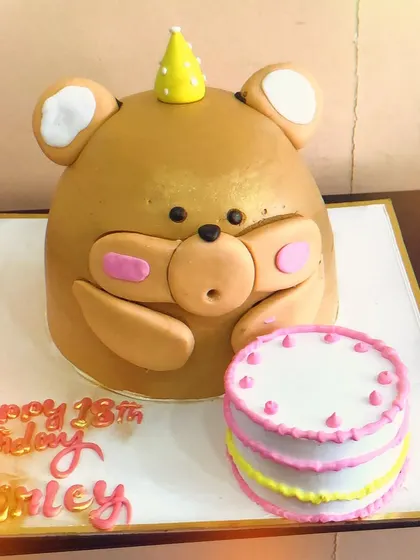 Another view of the giant teddy bear cake, highlighting its cute expression and the mini cake alongside it. We love bringing our clients' creative ideas to life.