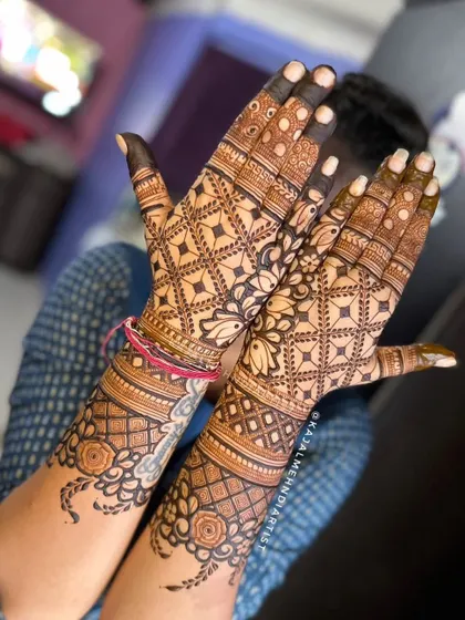 A beautiful Indian henna design featuring lotus flowers and grid patterns. The back of the hands are adorned with floral bands, creating a complete and balanced look.