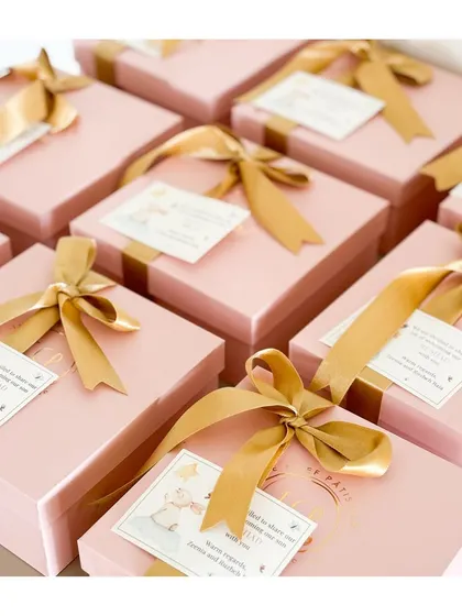 Pink joy has arrived! These beautiful pink boxes tied with a golden ribbon are perfect for announcing the birth of a little girl.