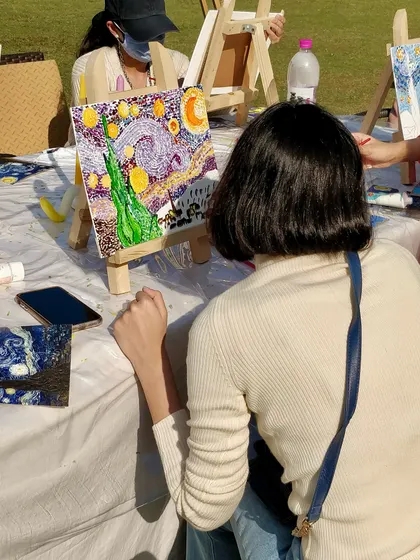 A participant admires her nearly finished pointillist-style 'Starry Night' painting.