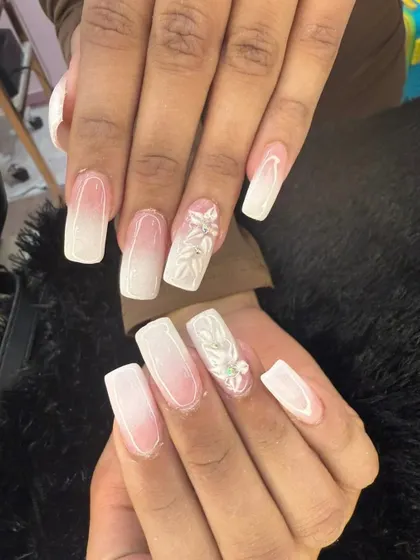 A beautiful example of modern bridal nails. This set features a soft white ombre on a squared nail shape, with intricate 3D floral accents on a few nails for a touch of texture and romance.