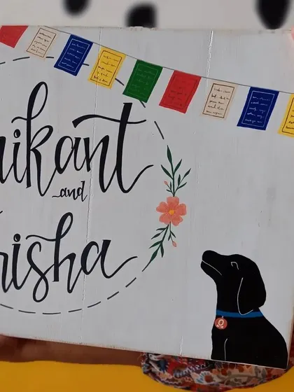 A duplicate of 73, a close-up on the hand-painted details of the "Srikant and Trisha" name board, showing the delicate flower and the silhouette of their dog.