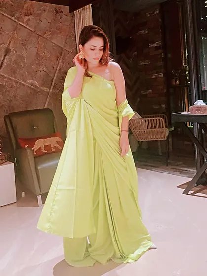 The one-shoulder cut and draped silhouette of this neon outfit offer a modern alternative to a traditional saree. It’s a great example of how we can play with contemporary ethnic wear for parties.