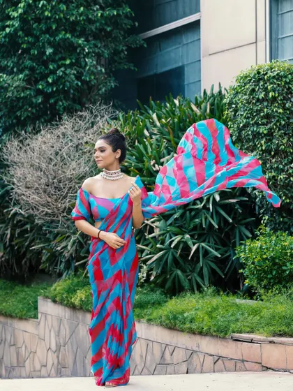 Capturing a colorful saree in motion against a green, natural backdrop. The flowing pallu creates a sense of dynamism and freedom, highlighting the lightweight fabric.