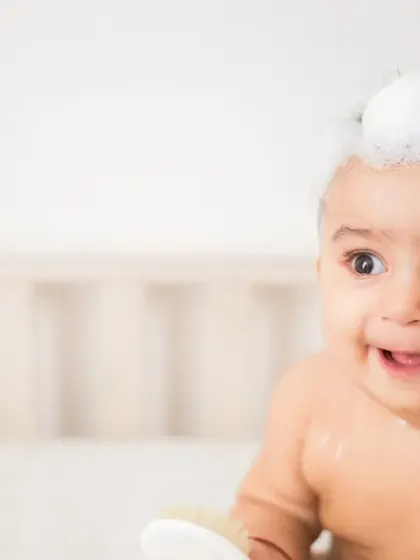 This candid shot captures a baby's curious expression during bath time. The soft focus and bright lighting create a gentle, dreamy quality, perfect for a skincare brand's visual story.