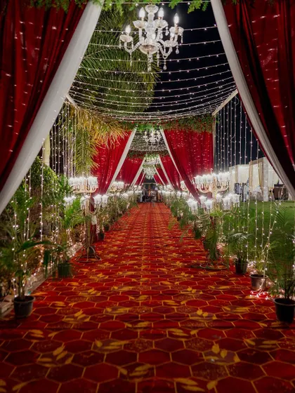 The royal red carpet entrance, ready to welcome guests to a magnificent reception. The combination of rich fabrics, warm lighting, and grand chandeliers creates an unforgettable sense of arrival.