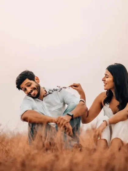A candid moment of laughter during a pre-wedding shoot in a golden field, capturing the couple's genuine joy.