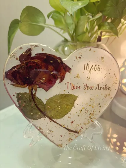 A simple yet powerful design. This heart-shaped resin block preserves a single red rose, complete with its stem and leaves. The piece is personalized with a date and a loving message, making it a deeply personal gift.