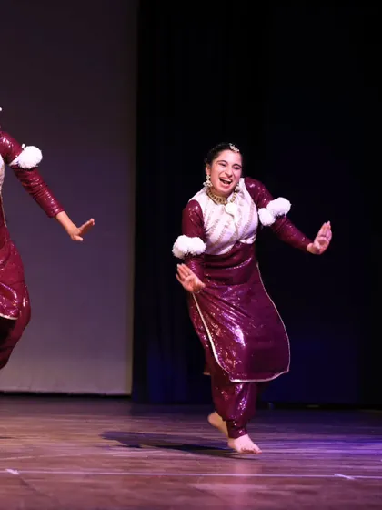 Two performers from the Bhangra Queens share a moment of fun and connection during their energetic folk routine.