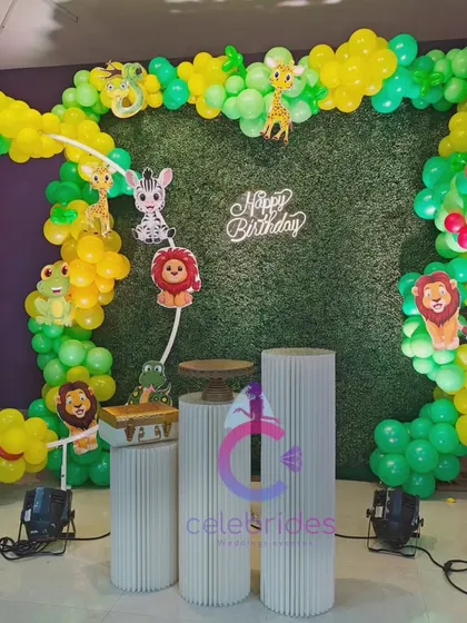 A vibrant jungle-themed birthday party decoration. We used green and yellow balloons to create a circular arch and a tree, with cute animal cutouts to complete the look.