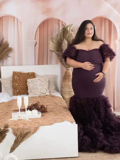 A serene portrait of a mom-to-be in our boho bedroom setup. The rich purple gown and soft textures create a cozy and luxurious feel.