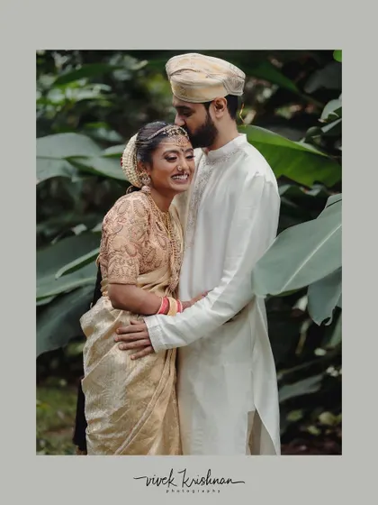 A tender moment between a couple, captured in a beautifully framed portrait. The groom's gentle kiss on the bride's forehead is a perfect picture of love and affection.