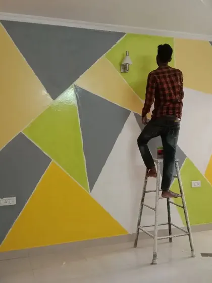 Our artist carefully works on a multi-colored geometric wall, ensuring each section is painted perfectly for a flawless final result.
