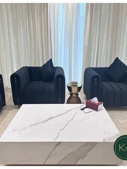 This shot highlights the two matching armchairs from the navy blue tufted set. The vertical tufting and studded details on the arms showcase our attention to fine detailing in every piece.