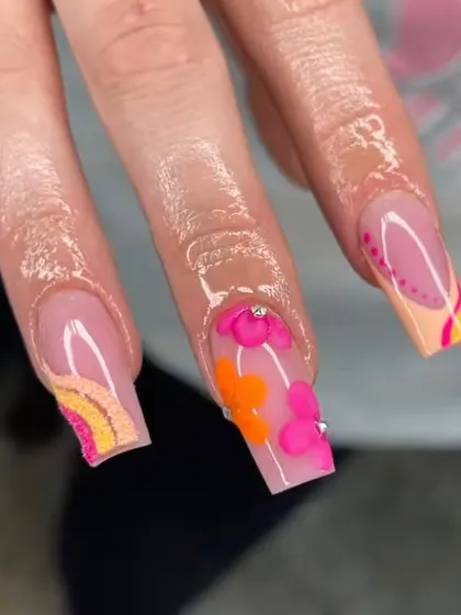 A close-up of the intricate, multi-colored floral and rainbow nail art, showing the detailed layering and 3D elements.