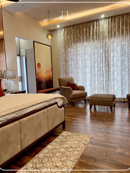 This bedroom features rich wooden flooring and a large, comfortable bed with warm-toned furnishings. The large painting adds a personal and artistic touch to the space.