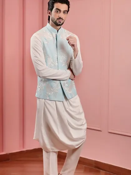 A classic and elegant combination. This powder blue Nehru jacket with white tonal embroidery is layered over a draped white kurta, creating a sophisticated look for any formal occasion.