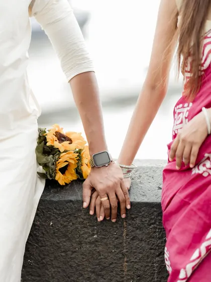 A close-up detail shot of the couple's hands, showing the engagement ring and traditional bangles. This focuses on the small, meaningful details of their union.