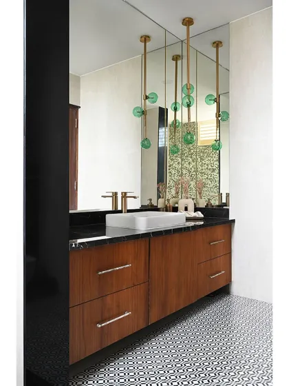 This powder room makes a bold statement with its patterned floor tiles and dramatic pendant lighting. The large mirror enhances the sense of space, while the wooden vanity adds a natural, grounding element.