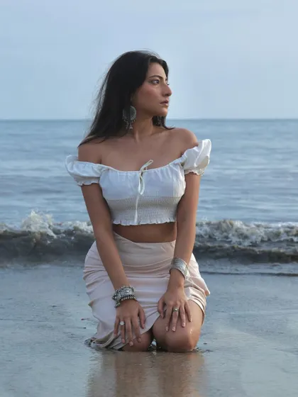 A serene moment captured by the water's edge. The soft, diffused light of the overcast sky creates a gentle and contemplative mood for this beach portrait.