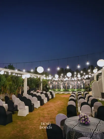 An elegant outdoor seating arrangement for a "Starry Night" themed sangeet, with a canopy of paper lanterns and string lights.