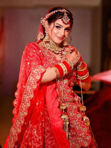 A joyful portrait of a bride in a classic red lehenga, her smile lighting up the frame.