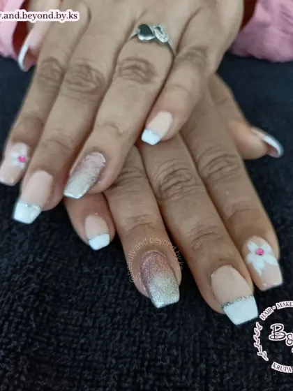 Taking the classic French manicure up a notch. These acrylic extensions feature white tips with a silver glitter line, a pink and silver glitter ombre accent, and a delicate hand-painted flower.