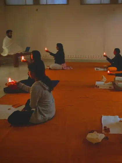 The warm glow of ghee lamps illuminates the room during a Bhuta Shuddhi session, creating a sacred and potent atmosphere.