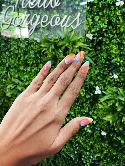 A vibrant and colorful abstract design perfect for summer. We used shades of orange, blue, and pink to create this fun, swirly pattern on long almond nails.
