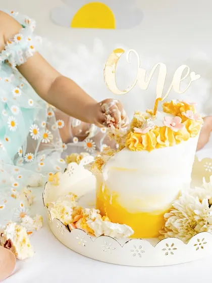 A close-up of tiny hands digging into a beautifully decorated first birthday cake. These detail shots are a fun part of every cake smash session.