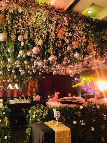 A view of the sangeet hall with a ceiling dripping with greenery and disco balls, creating a wild and glamorous party atmosphere.