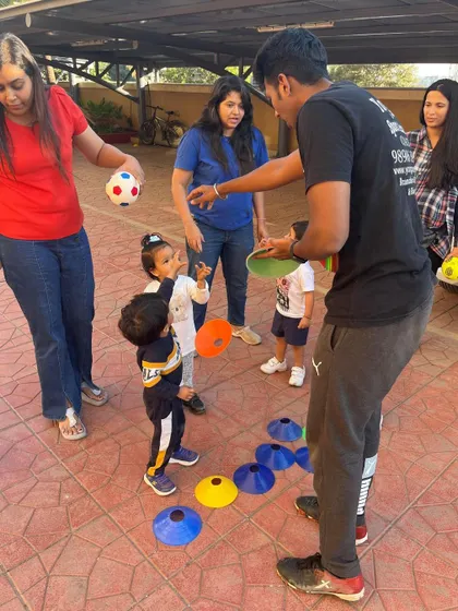 A coach engages a group of toddlers and their parents in a fun activity with cones. Our toddler classes are designed to be interactive for the whole family.