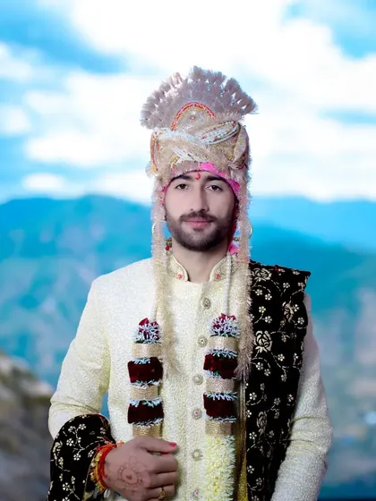 A classic, front-facing portrait of the groom, showcasing his complete wedding look from the turban to the sherwani.