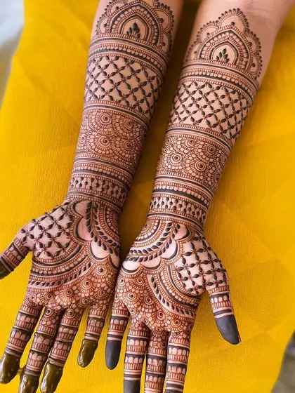 Full bridal mehandi with heavy, intricate patterns covering both hands and extending up the arms. This design uses traditional check patterns, floral motifs, and detailed finger work for a classic bridal look.