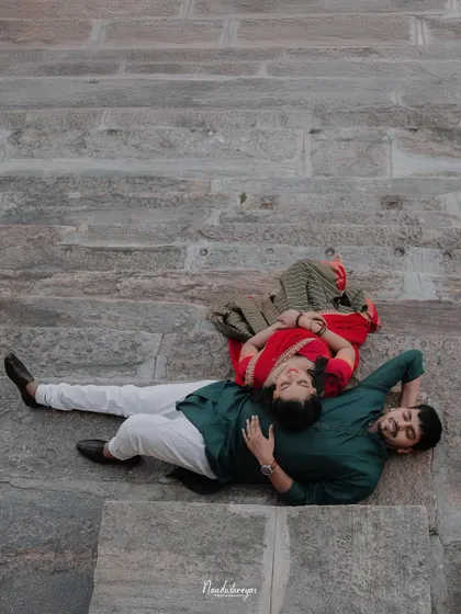 A relaxed, unconventional pose with the couple lying on the stone steps of a temple, seen from above.