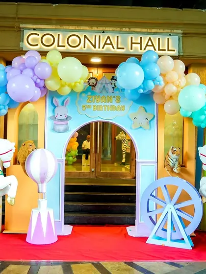 The grand entrance to the 'Colonial Hall' for a pastel carnival birthday, framed by carousel horses and beautiful balloon arches.
