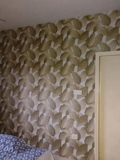 A bedroom with a neutral-toned leaf pattern wallpaper, creating a calm and soothing atmosphere.