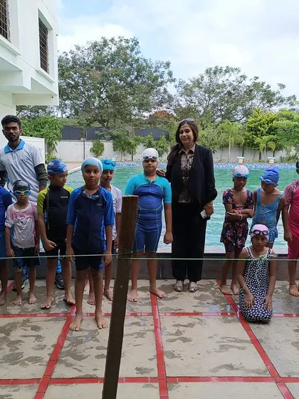 A group of young swimmers poses with their coaches and our principal after a successful swimming competition. We encourage sports from an early age.