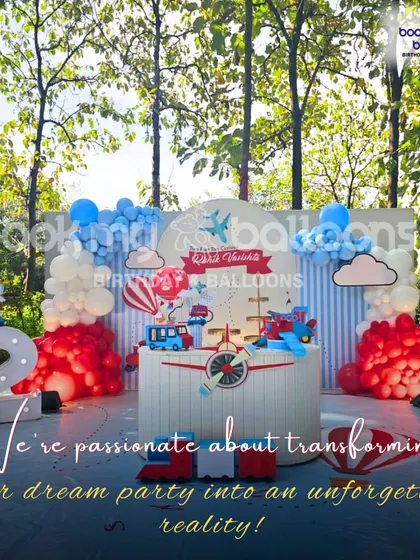 This outdoor transportation theme was perfect for a second birthday. The setup featured a vintage plane, a train, and a bus, all made charming with red and blue decor against a natural, wooded backdrop.