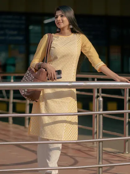 A modern lifestyle shot for Zouk bags. I am dressed in a comfortable yellow kurti, showing how the handcrafted bag is a perfect accessory for travel and daily commutes.