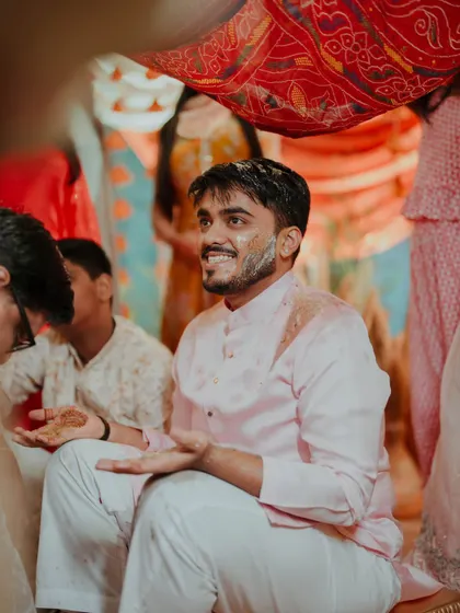 The groom enjoying the Haldi rituals, seated under a traditional decorated cloth. We ensure that even the most candid moments are beautifully framed.