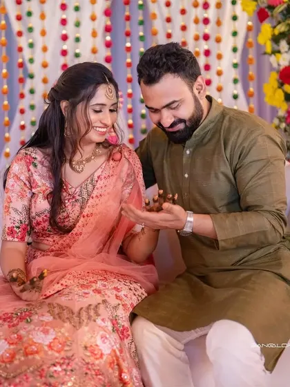 A sweet moment during the Mehendi ceremony. The groom's gentle gesture and the bride's happy smile tell a story of love and shared traditions.