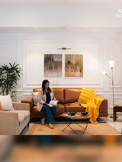 In this living room at Ireo Skyon, we used classic wall mouldings to add a touch of sophistication. A warm leather sofa, layered lighting, and abstract art create a cozy and stylish ambiance.
