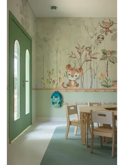 Welcome to the forest-themed classroom for LKG students. A friendly tiger peeks out from the custom wallpaper, set against a backdrop of soft green tones. The modular birch ply furniture is both beautiful and functional.